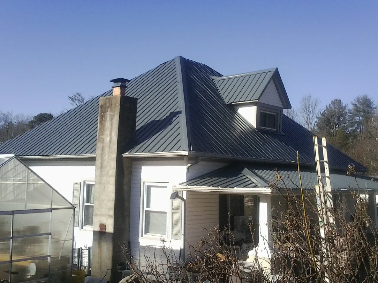 Dark blue standing seam metal roof on a white farmhouse with dormer — Slate & Tile Roof Repair by Roofing Brothers in El Segundo