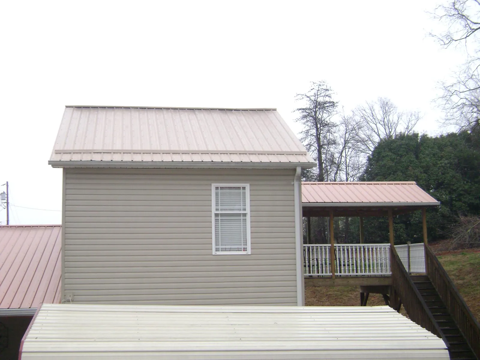 Tan metal roofs on a two story addition and attached porch, from a Roof Replacement job in El Segundo